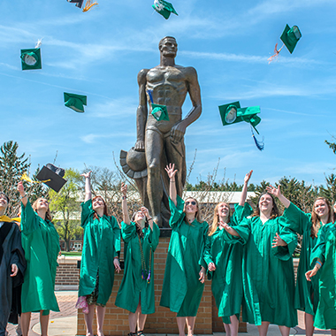 Graduates celebrate at the Sparty statue on the MSU campus. 
